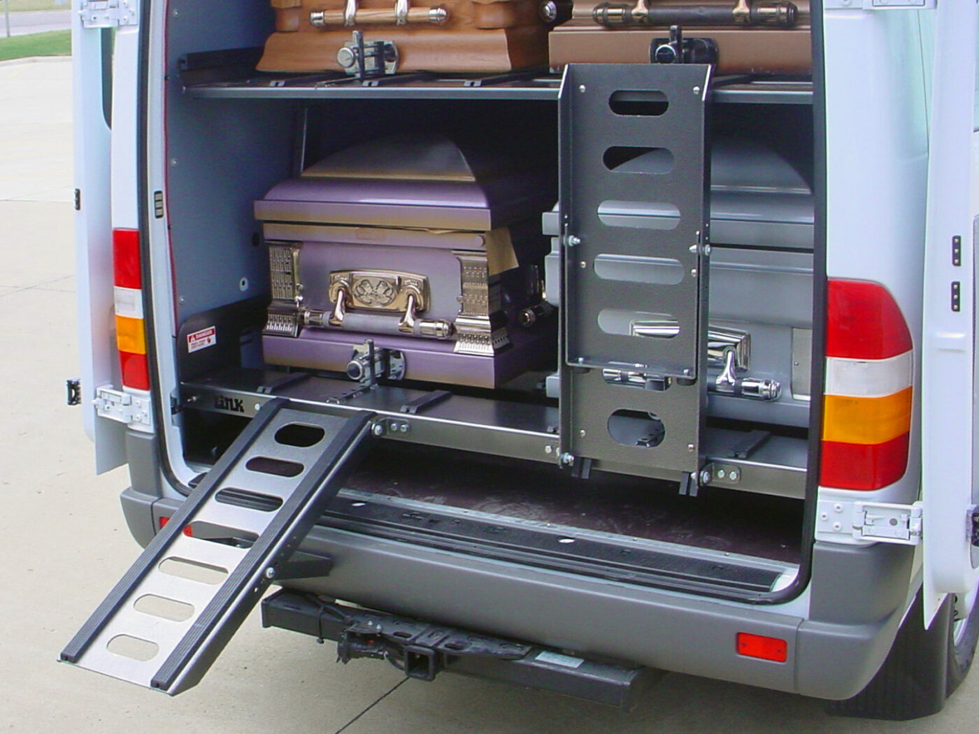 AME-DD4000 powered upper deck tilted down loading position — American Mortuary Equipment double-deck casket hauler for Sprinter and ProMaster vans