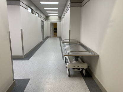 Oversized hydraulic embalming table stainless steel convex top and perimeter drainage trough in a funeral home prep room